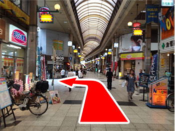 突き進んで、最初の商店街の交差しているオリジン弁当を超えた所を左です。
